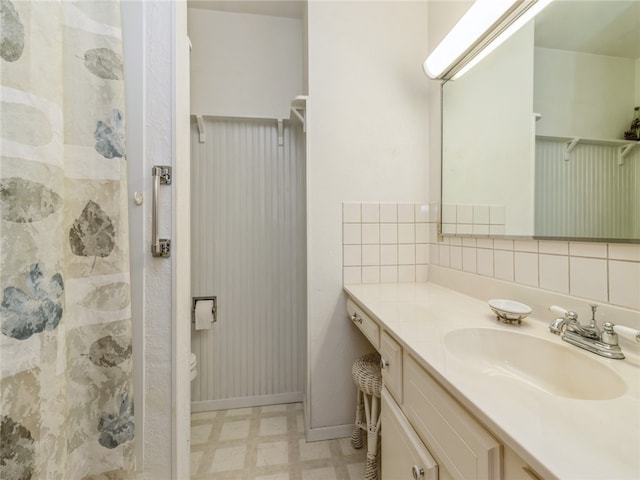 bathroom with decorative backsplash, tile walls, toilet, vanity, and tile patterned flooring