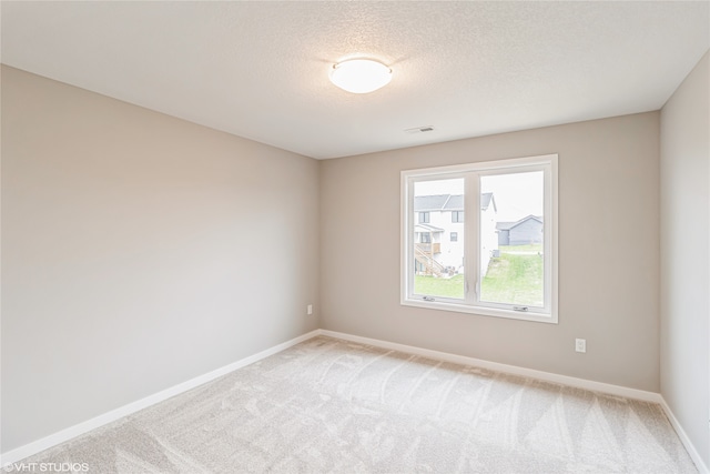 carpeted empty room featuring a textured ceiling