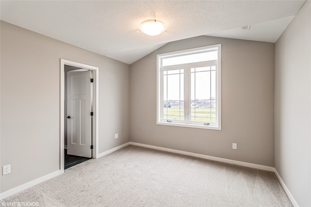 unfurnished room with a textured ceiling, carpet, and lofted ceiling