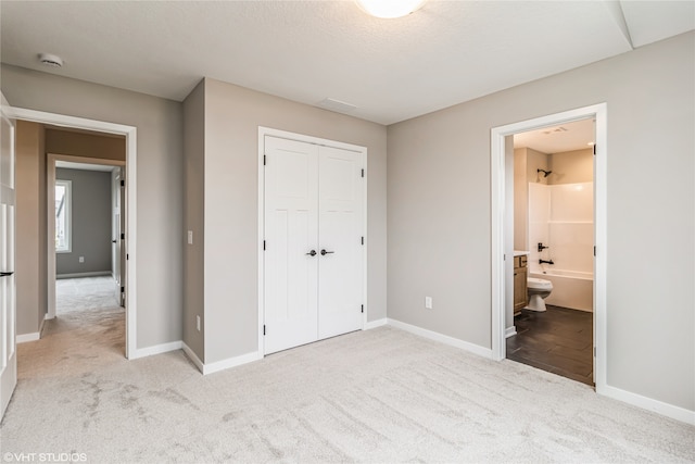 unfurnished bedroom featuring light carpet, a closet, and connected bathroom