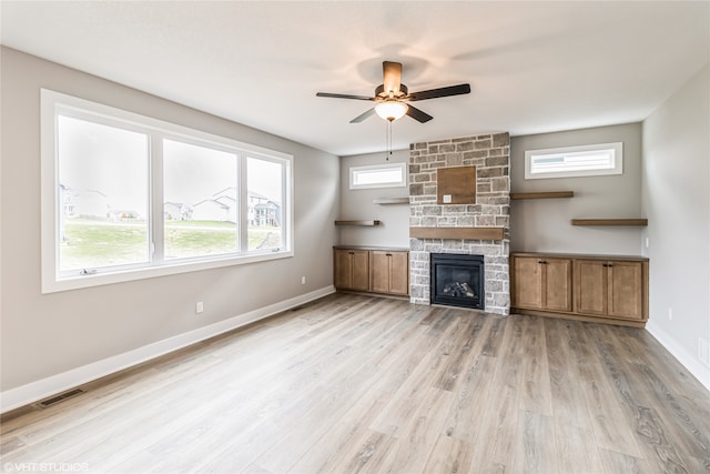 unfurnished living room with ceiling fan, a fireplace, and light hardwood / wood-style flooring