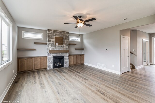 unfurnished living room featuring ceiling fan, a fireplace, and light hardwood / wood-style flooring