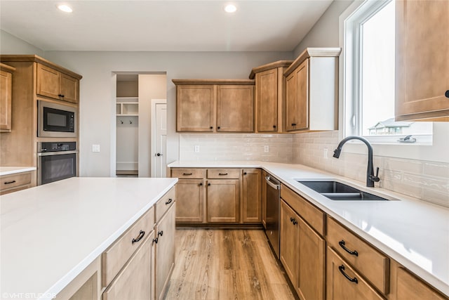 kitchen featuring light wood-type flooring, appliances with stainless steel finishes, backsplash, and sink