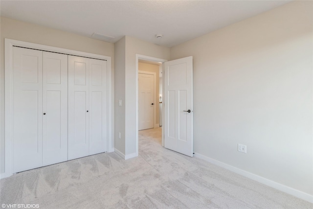 unfurnished bedroom with light carpet and a closet