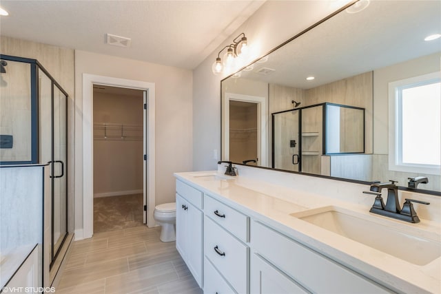 bathroom featuring toilet, a textured ceiling, walk in shower, and vanity