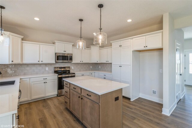 kitchen featuring pendant lighting, appliances with stainless steel finishes, a kitchen island, white cabinetry, and sink