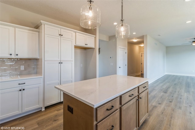 kitchen with light hardwood / wood-style floors, a kitchen island, decorative backsplash, hanging light fixtures, and white cabinets