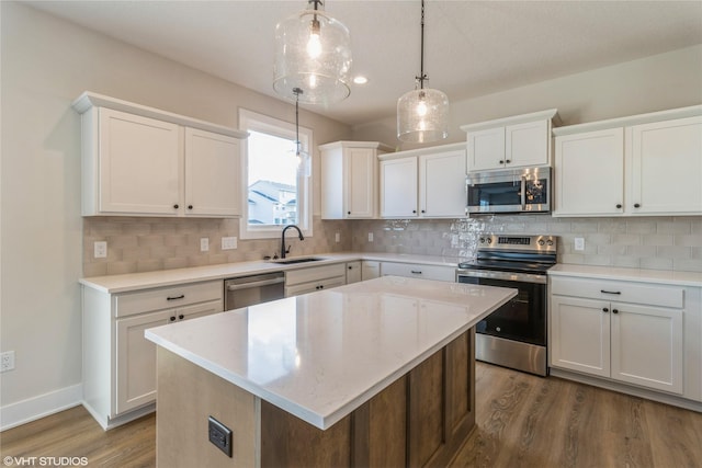 kitchen featuring white cabinets, pendant lighting, stainless steel appliances, and a center island