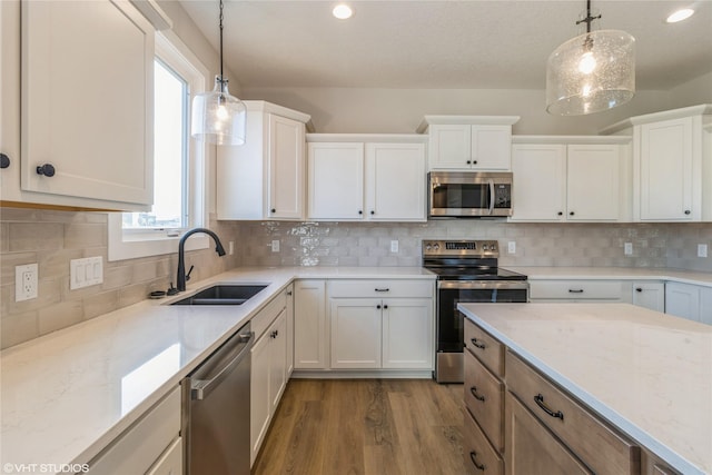 kitchen featuring sink, pendant lighting, stainless steel appliances, and white cabinetry