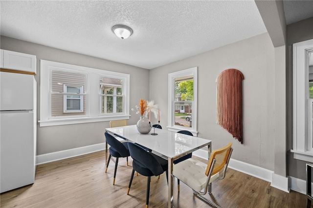 dining room featuring light hardwood / wood-style flooring and a textured ceiling