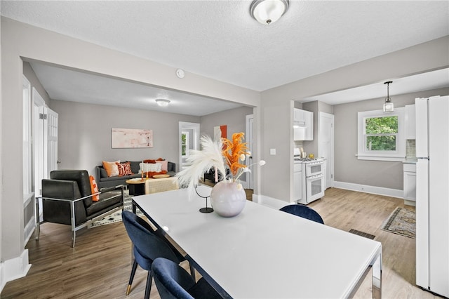 dining area with a textured ceiling and light wood-type flooring