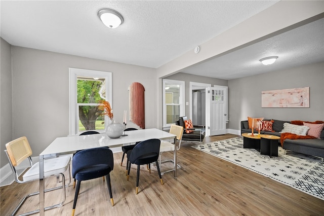 dining space with a textured ceiling and light hardwood / wood-style floors