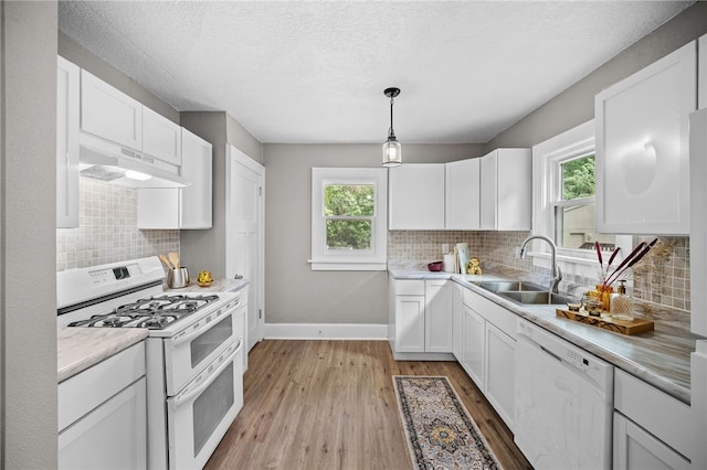 kitchen featuring decorative backsplash, custom exhaust hood, white appliances, and light hardwood / wood-style floors