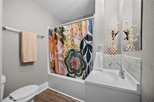 full bathroom with a textured ceiling, toilet, wood-type flooring, shower / bath combo, and vanity