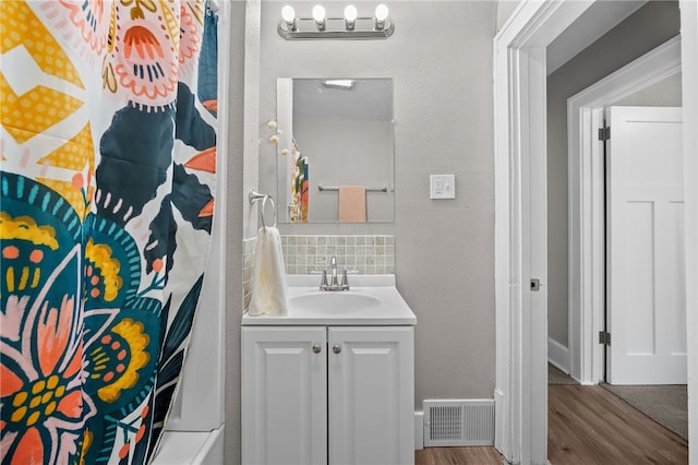 bathroom with hardwood / wood-style floors, tasteful backsplash, and vanity