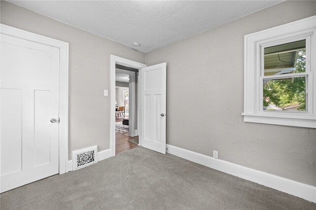 unfurnished bedroom featuring a textured ceiling and carpet