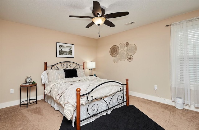 carpeted bedroom with ceiling fan and a textured ceiling