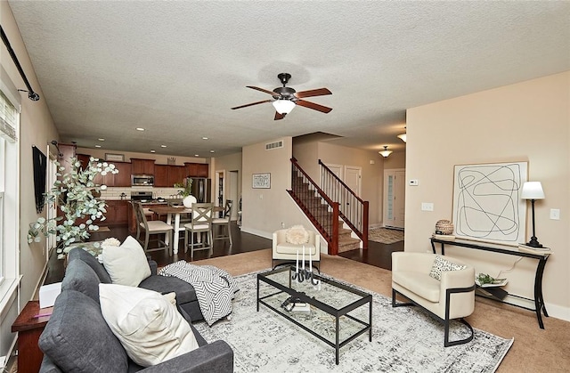 carpeted living room with ceiling fan and a textured ceiling