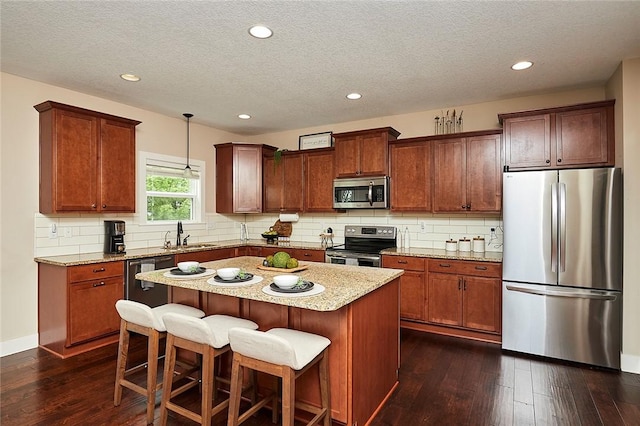 kitchen featuring appliances with stainless steel finishes, decorative light fixtures, a kitchen breakfast bar, a center island, and dark wood-type flooring