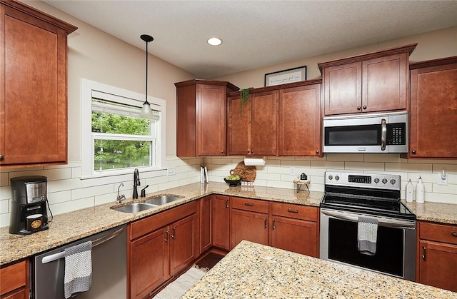 kitchen featuring pendant lighting, sink, appliances with stainless steel finishes, light stone countertops, and decorative backsplash