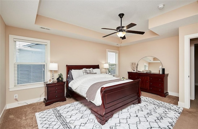 bedroom featuring light colored carpet, ceiling fan, and a tray ceiling