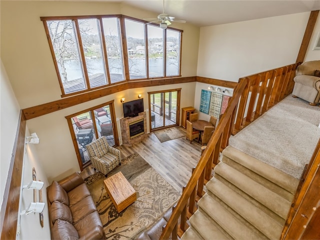 living room with ceiling fan, a high ceiling, and light hardwood / wood-style floors