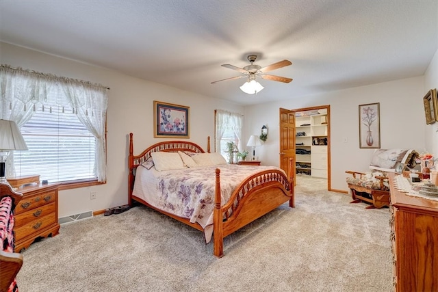 bedroom featuring light carpet, ceiling fan, and multiple windows