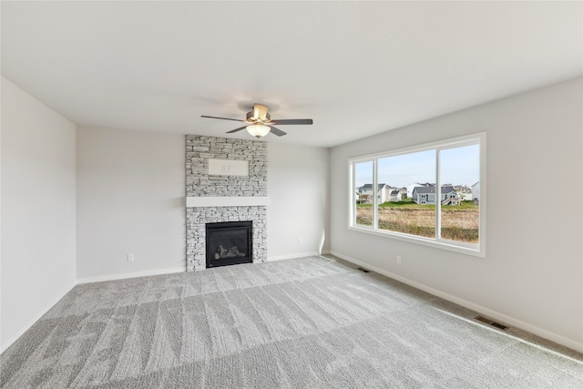 unfurnished living room featuring ceiling fan, a fireplace, and light colored carpet