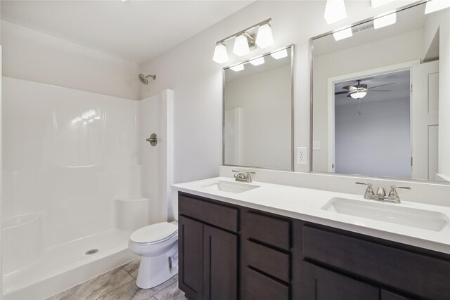 bathroom featuring ceiling fan, toilet, walk in shower, and vanity