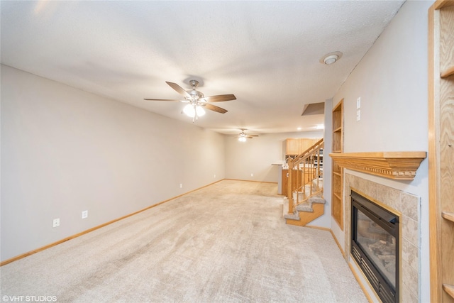 carpeted living room with a tiled fireplace and ceiling fan