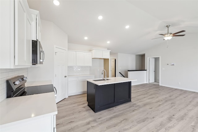 kitchen with appliances with stainless steel finishes, white cabinetry, sink, backsplash, and a center island with sink