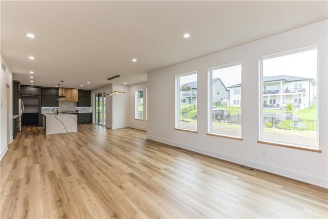 unfurnished living room with light wood-type flooring and sink