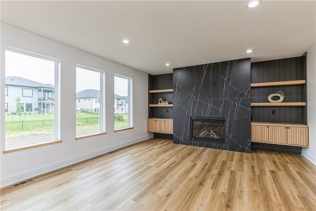 unfurnished living room featuring light hardwood / wood-style flooring and a high end fireplace