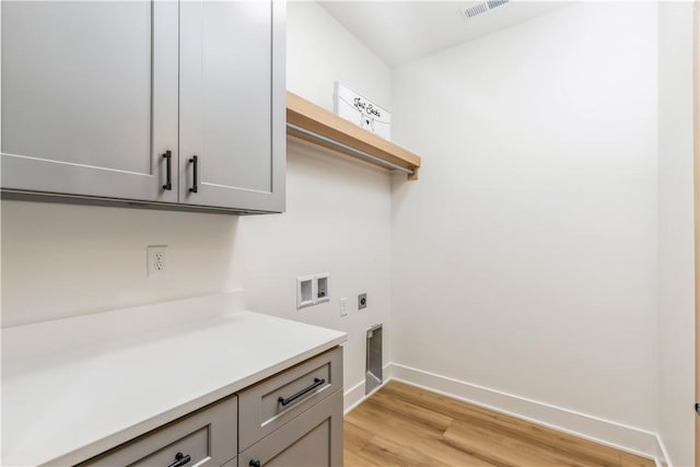 clothes washing area with hookup for a washing machine, cabinets, light hardwood / wood-style flooring, and hookup for an electric dryer