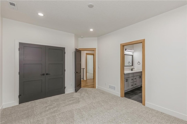 bedroom featuring sink, dark colored carpet, a closet, and ensuite bathroom