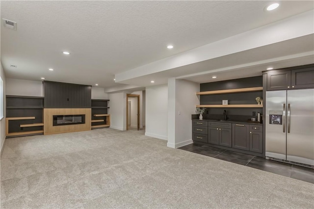 unfurnished living room featuring a fireplace, dark carpet, and a textured ceiling