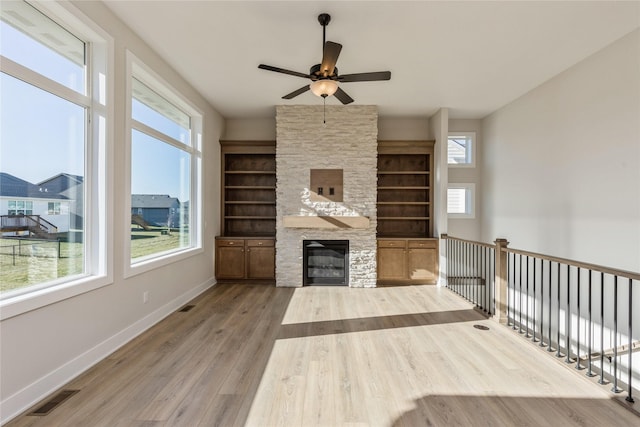 unfurnished living room featuring hardwood / wood-style flooring, ceiling fan, and a fireplace