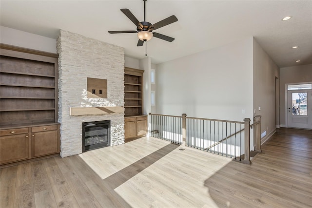 living room with ceiling fan, a fireplace, and light hardwood / wood-style flooring