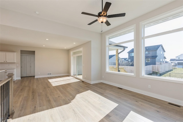 living room with a wealth of natural light, ceiling fan, and light wood-type flooring