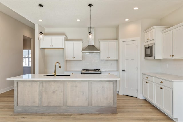 kitchen featuring a center island with sink, white cabinets, light wood-type flooring, and hanging light fixtures