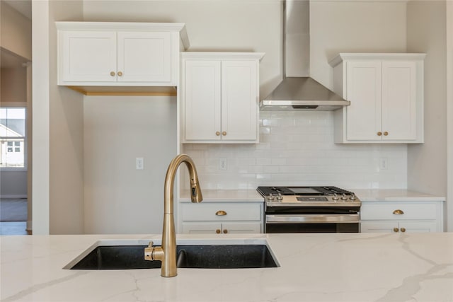 kitchen featuring white cabinets, sink, wall chimney exhaust hood, stainless steel gas stove, and light stone counters