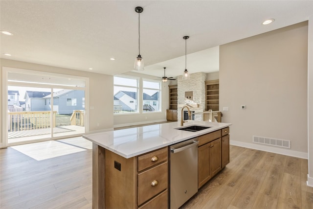 kitchen featuring sink, light hardwood / wood-style flooring, dishwasher, a center island, and hanging light fixtures