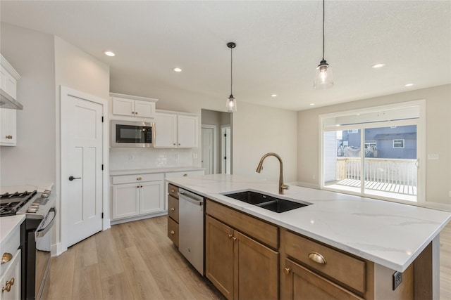 kitchen featuring sink, an island with sink, pendant lighting, white cabinets, and appliances with stainless steel finishes