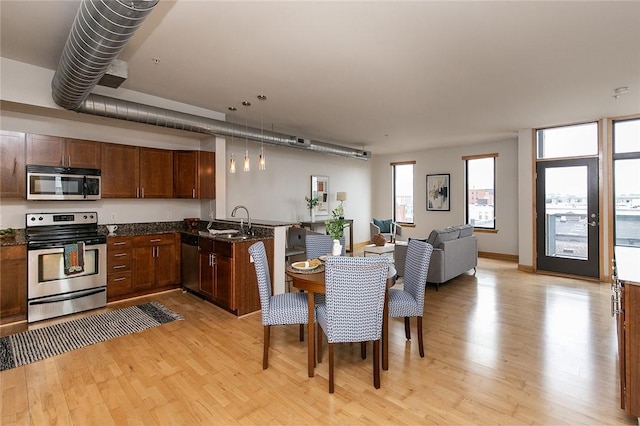 kitchen featuring sink, light hardwood / wood-style flooring, appliances with stainless steel finishes, kitchen peninsula, and pendant lighting