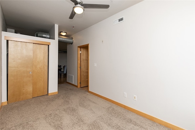 unfurnished bedroom with ceiling fan, light colored carpet, and a closet