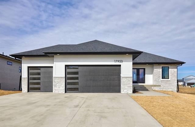 prairie-style house with concrete driveway, a shingled roof, an attached garage, and stone siding