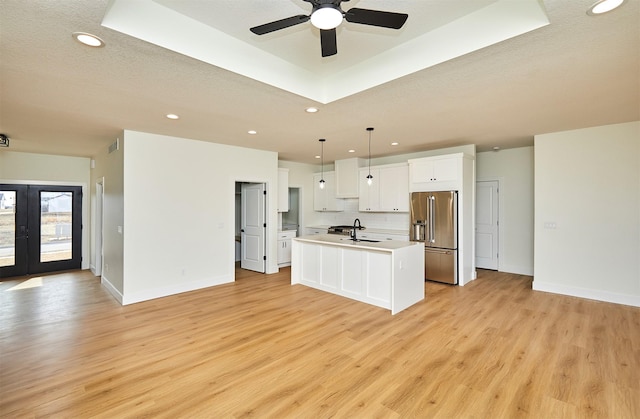 kitchen featuring high end refrigerator, white cabinetry, french doors, light wood-type flooring, and a tray ceiling