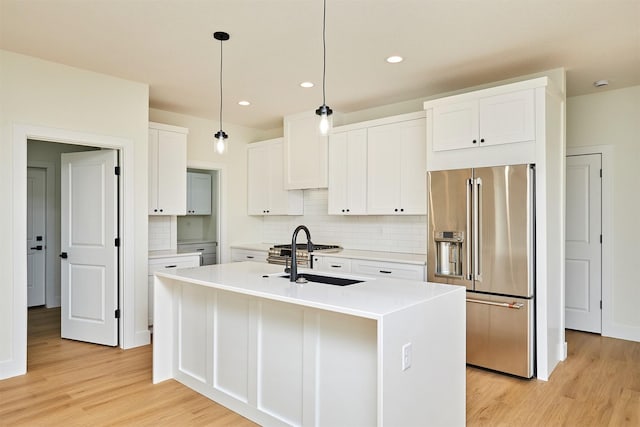 kitchen featuring white cabinets, high quality fridge, light wood-style flooring, and a sink