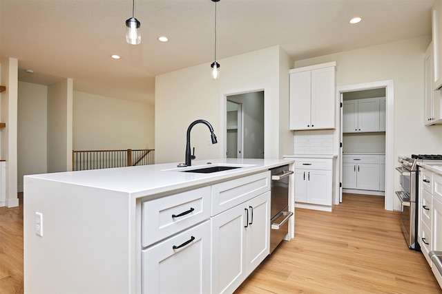 kitchen featuring decorative light fixtures, recessed lighting, light wood-style floors, a sink, and double oven range