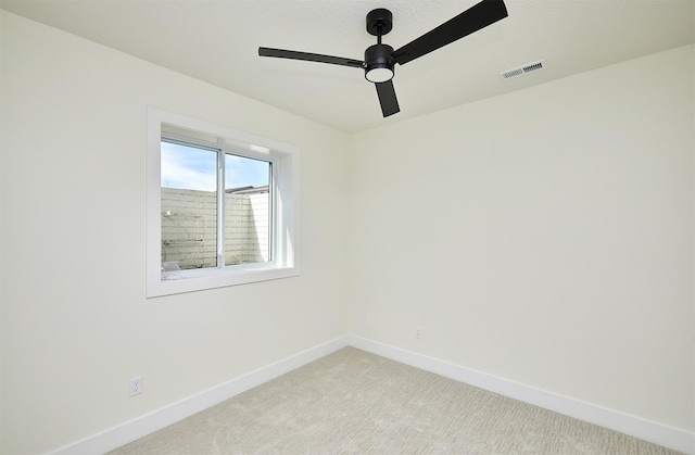 spare room featuring baseboards, visible vents, a ceiling fan, and light colored carpet